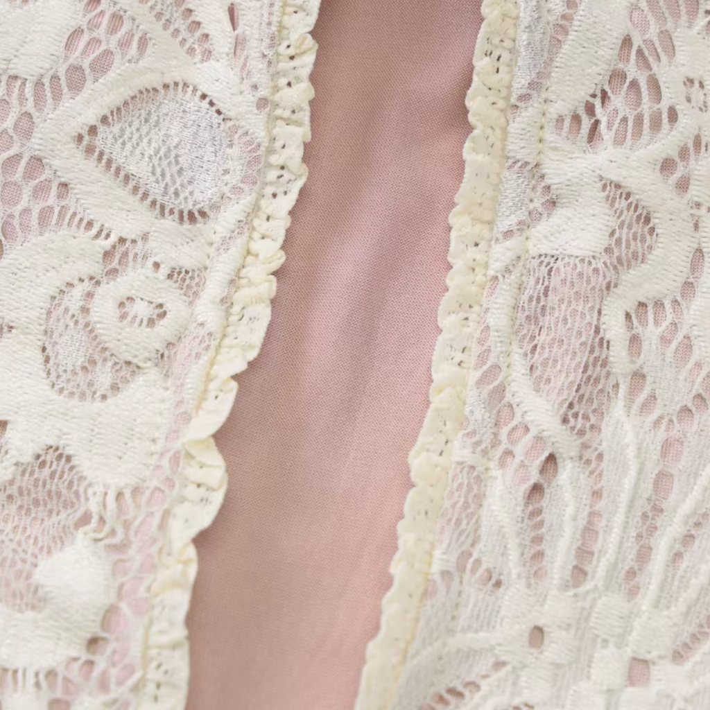 Detailansicht der feinen weißen Spitze und des rosafarbenen Stoffes des girlzhood Bellissima Nights Kleids