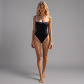 girlzhood Crimora Bodysuit in Schwarz mit weißen Kontrastkanten, getragen von einem Model vor grauem Hintergrund