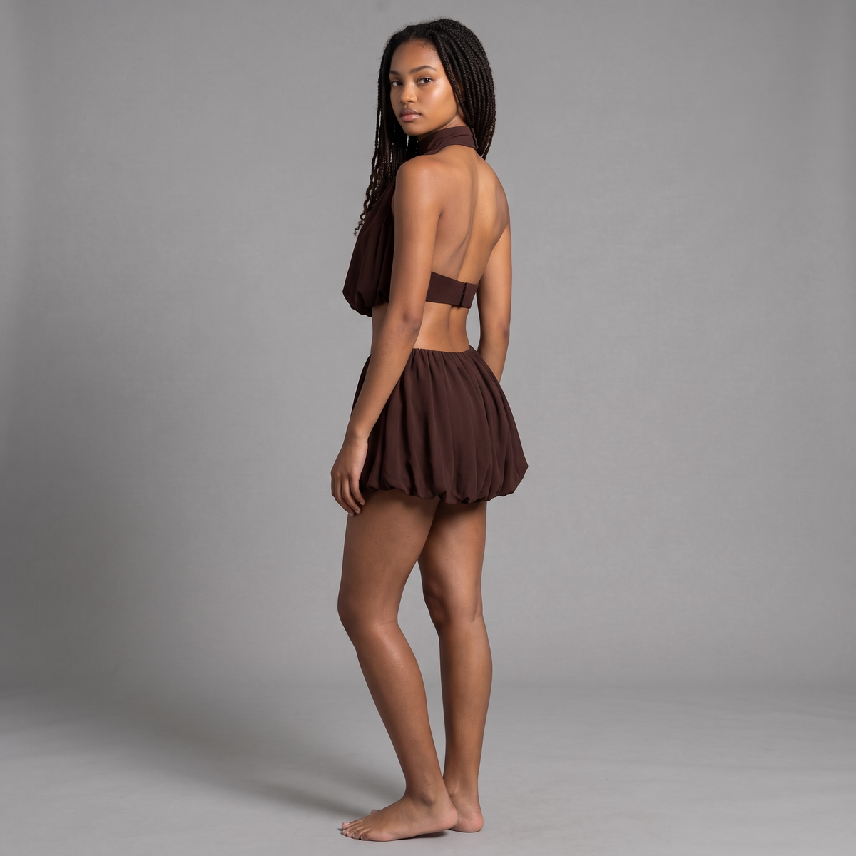 Model trägt das schokoladenbraune girlzhood Neckholder-Set mit rückenfreiem Ballon-Top und passenden Ballon-Shorts.