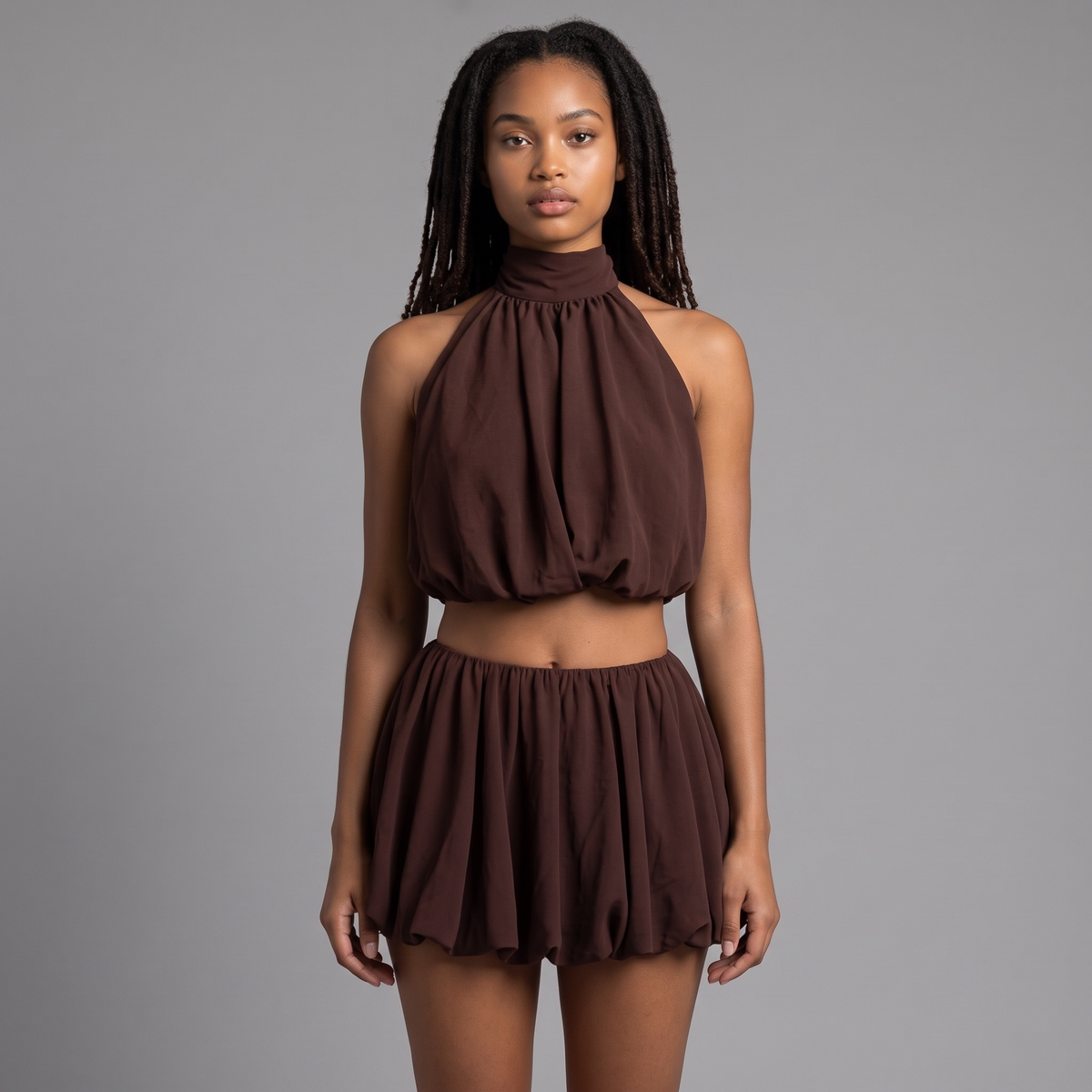 Model trägt girlzhood Brown Amor Set: schokoladenbraunes Neckholder-Top und Ballon-Shorts mit gerafftem Saum.