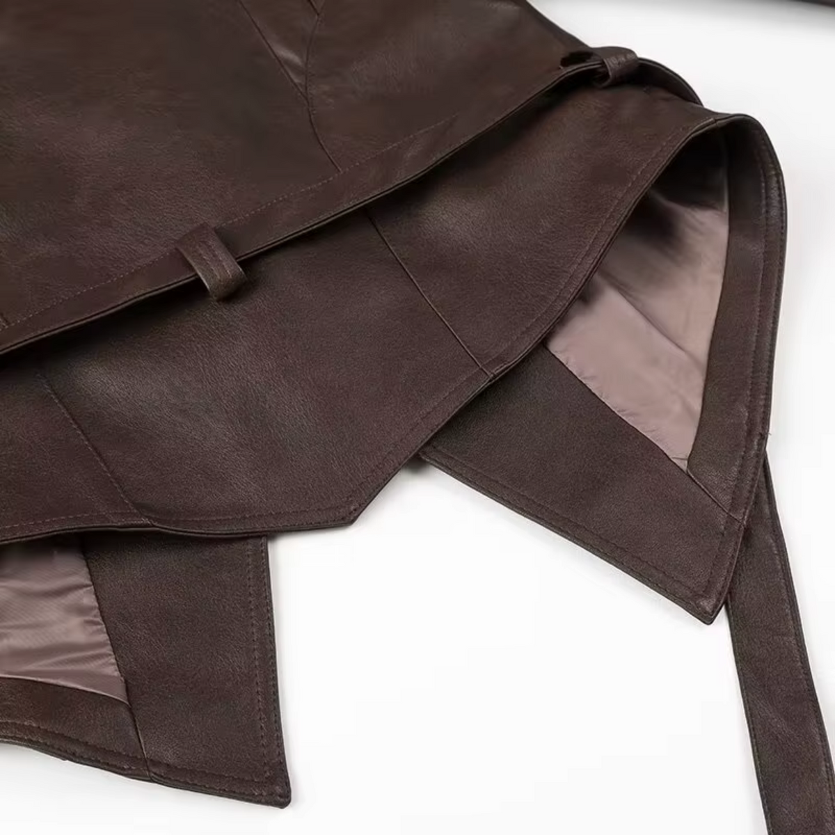 Detailansicht der braunen girlzhood Celestique Kunstlederjacke mit Bindegürtel und hochwertigem mattem Finish