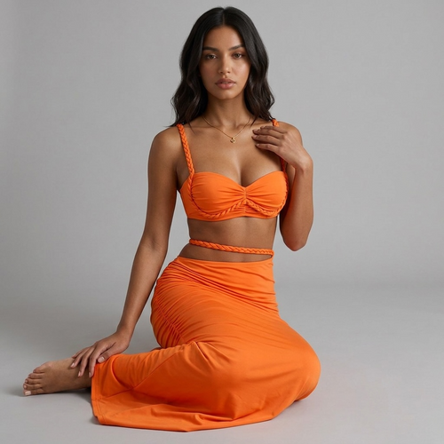 Model trägt das orangefarbene girlzhood Driftessa Set mit geflochtenem Crop-Top und figurbetontem Maxirock.