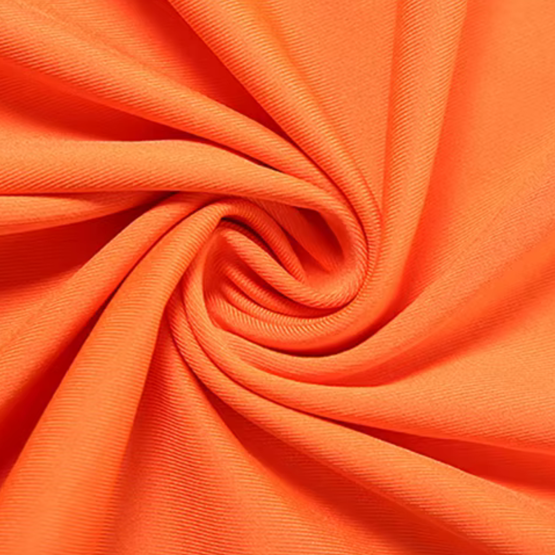 Nahaufnahme des orangefarbenen, weich glänzenden Stoffes vom girlzhood Driftessa Set in einer spiralförmigen Textur.