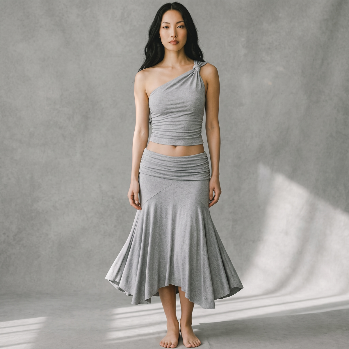 Model trägt girlzhood Sunny Set: graues One-Shoulder-Top und Maxirock mit geraffter Mermaid-Silhouette