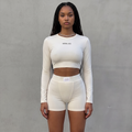 Model trägt girlzhood Longsleeve Duo Olivienne in Offwhite, bestehend aus Cropped Longsleeve und High Waist Shorts.