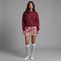 Model trägt girlzhood Luna Lace Satin Skirt in Rosa mit Spitzenbesatz, kombiniert mit bordeauxrotem Pullover