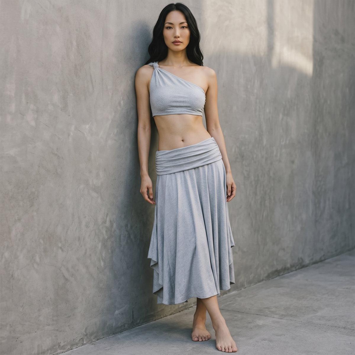 Model trägt das girlzhood Sunny Set: graues One-Shoulder Crop-Top und fließender Maxirock in minimalistischem Design.