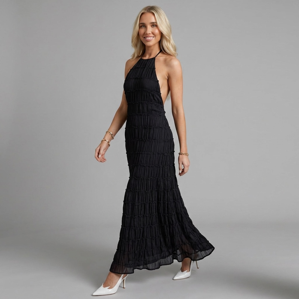 Blondes Model trägt das schwarze girlzhood Thermara Maxikleid mit Halterneck und plissiertem Design vor grauem Hintergrund