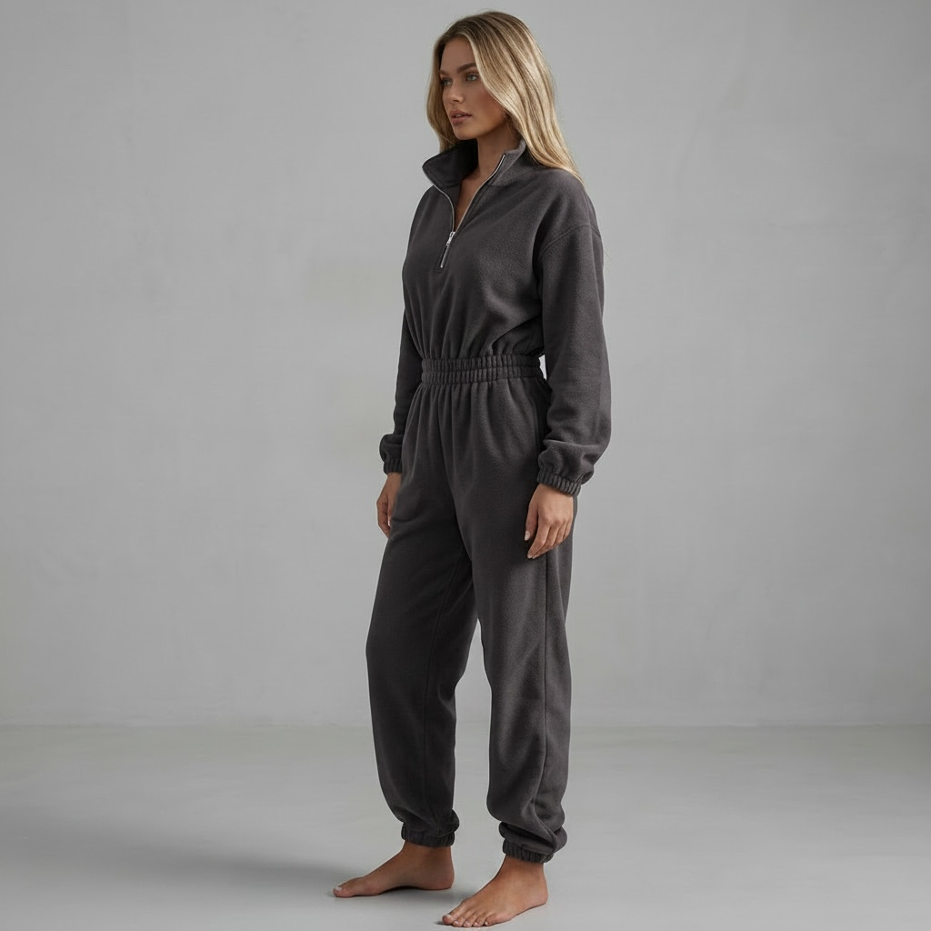 Model trägt girlzhood Urban Silence Jumpsuit in Anthrazit mit Half-Zip-Reißverschluss und elastischem Bund.