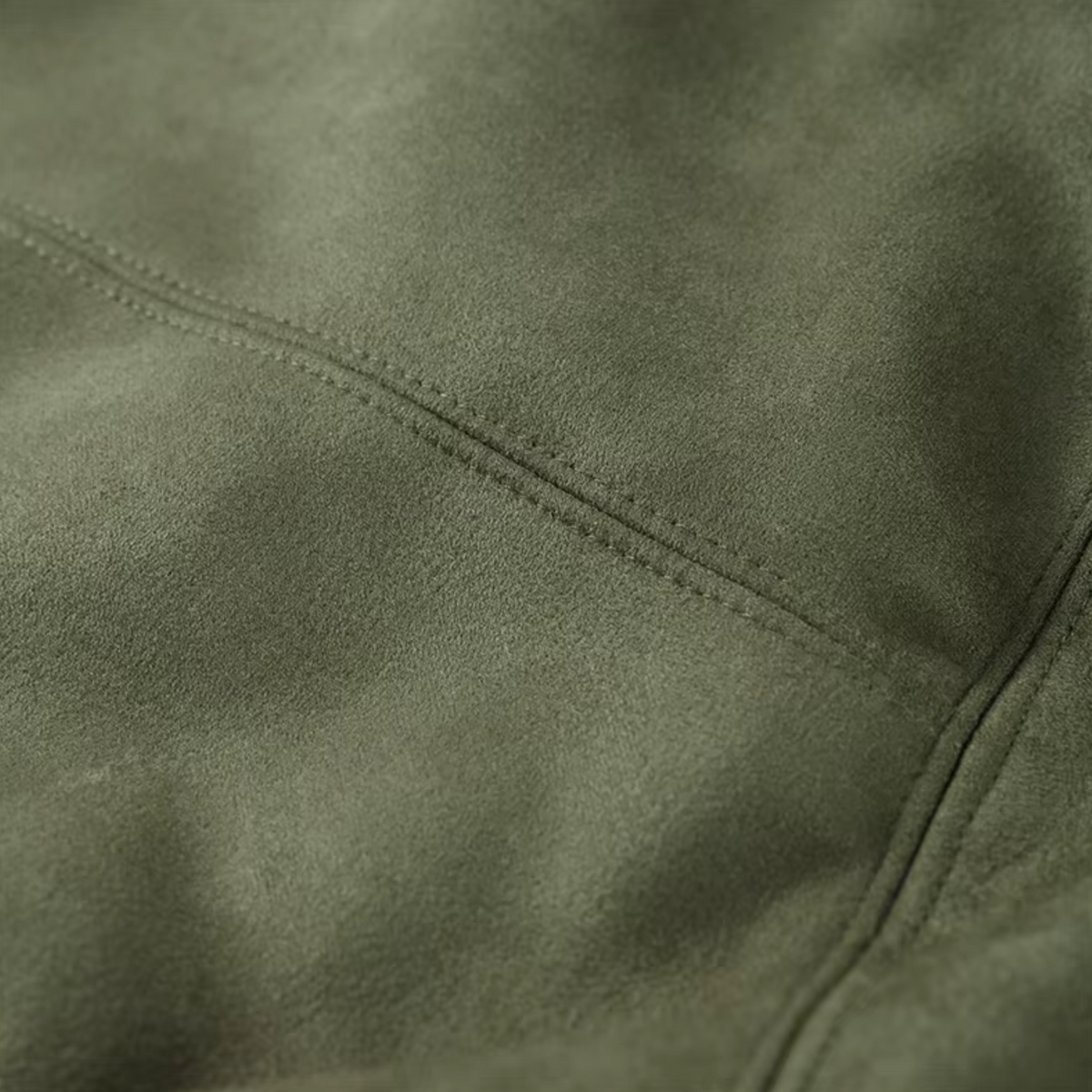 Nahaufnahme des samtweichen, olivgrünen Materials der girlzhood Valira Jacke mit präzisen Ziernähten