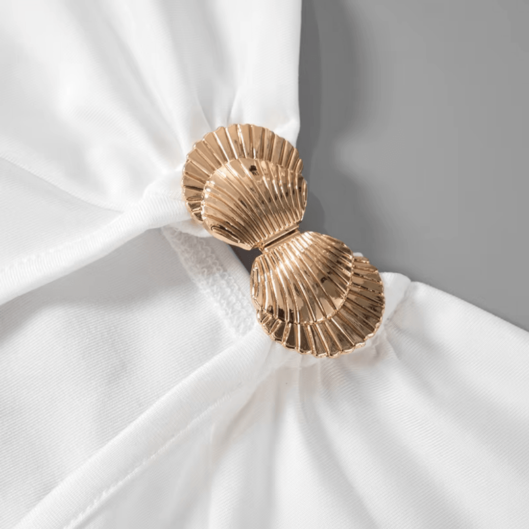 girlzhood Kleid Virelia in Weiß mit goldenem Muschel-Detail am Cutout für einen eleganten Sommer-Look