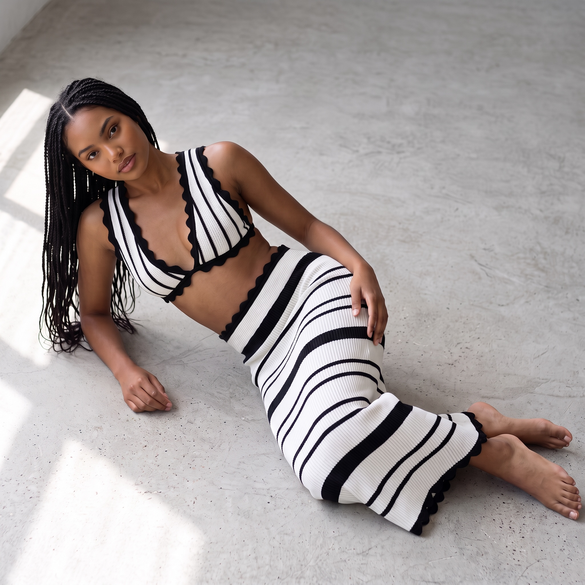 Model trägt girlzhood Virelle Zweiteiler aus schwarz-weißem Crochet mit Croptop und Maxi-Rock mit Wellenkanten