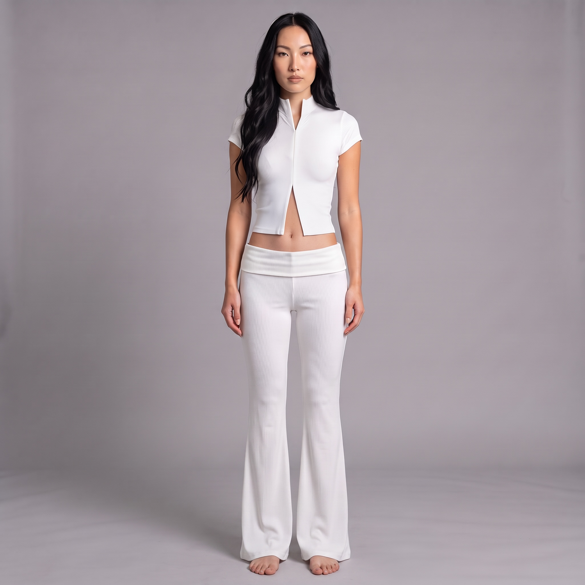 Model trägt das girlzhood Bold Touch 2-teilige Set in Weiß mit geripptem Oberteil und ausgestellter Hose
