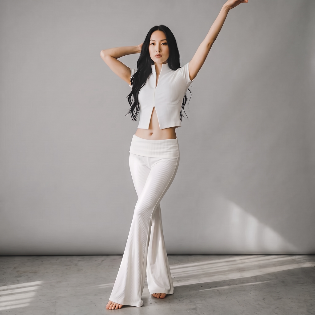 Model trägt das weiße girlzhood Bold Touch 2-Teiler Set mit geripptem Oberteil und ausgestellter Hose.